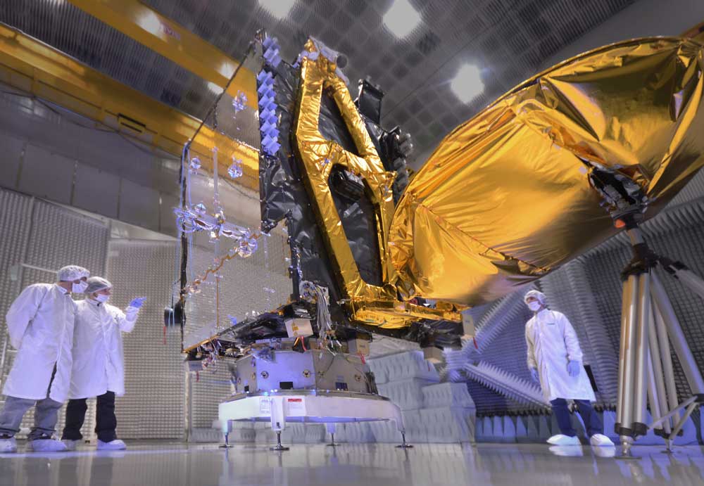 Tres ingenieros observando el cuerpo de un satélite en el Centro de Ensayos de Alta Tecnología Sociedad Anónima (CEATSA)